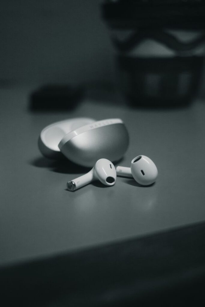 Minimalistic close-up of wireless earbuds with sleek design on a table in monochrome.